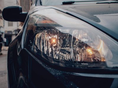 Detailed close-up of a car's headlight on a city street, showcasing urban automotive details.