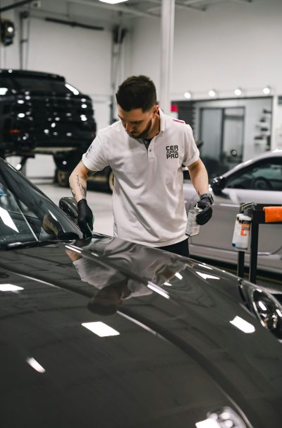 A dedicated employee expertly detailing a car hood in a clean, modern garage setting.